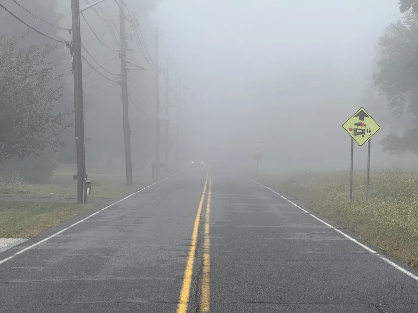 A foggy road in Mercer County, New Jersey, with a school bus warning sign