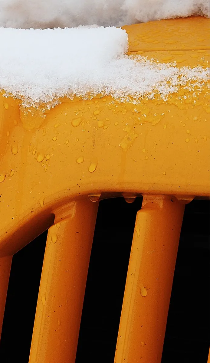 Snow settled on the grille of a yellow school bus